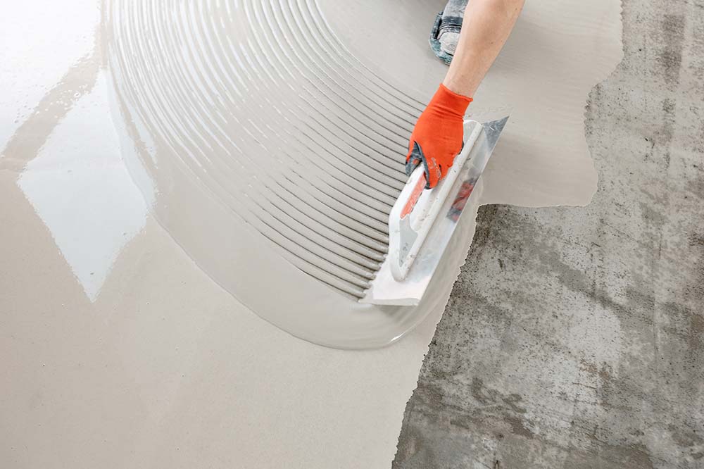 Self-leveling screed being applied to create the flat subfloor SPC flooring requires