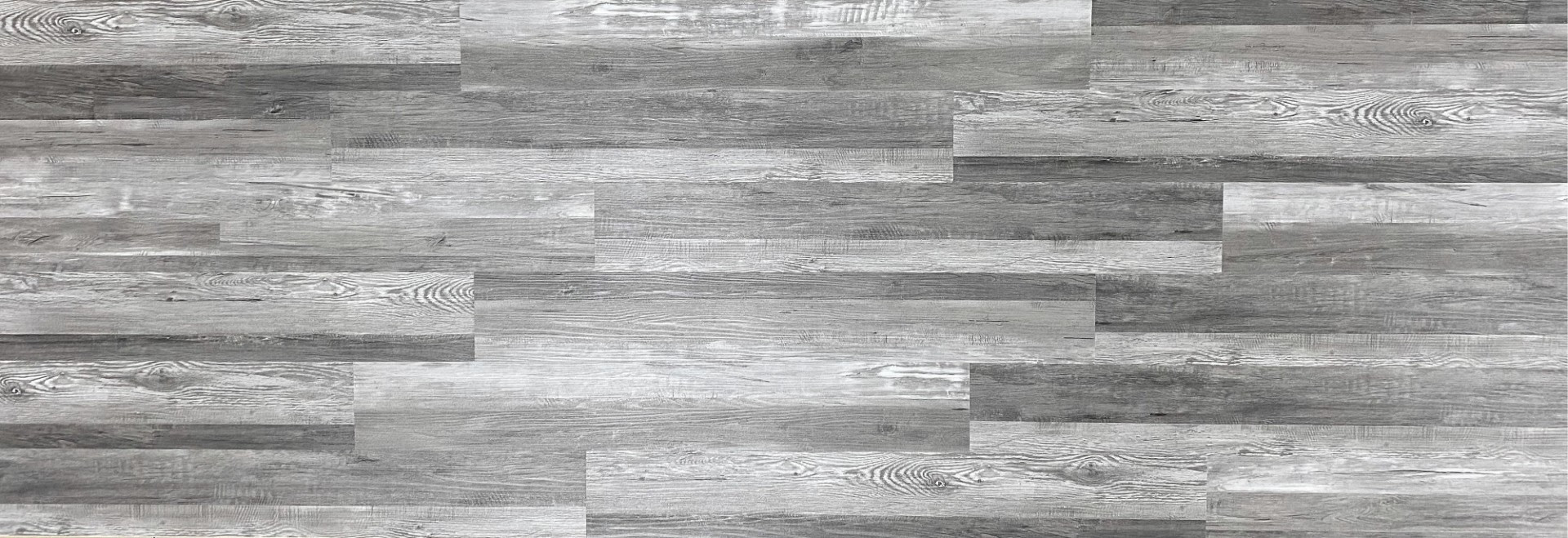 Grey wood-look SPC planks showing the rigid board construction and registered surface texture